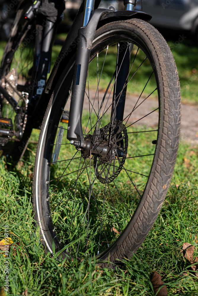 Close-up of a bicycle wheel on green grass.