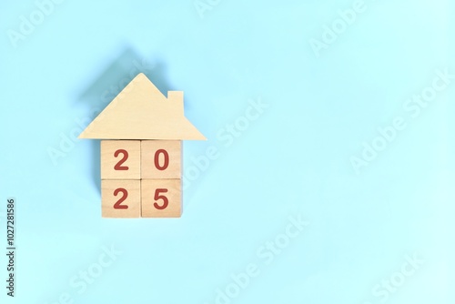 Obraz na płótnie Year 2025 home ownership goal and real estate property investment concept. Wooden blocks on blue background with icon. w salonie