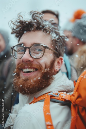 Cheerful man with glasses smiling in falling snow during a winter gathering outdoors photo