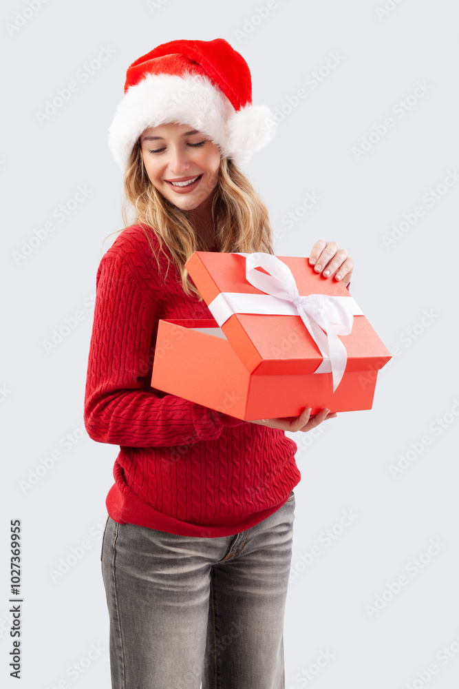 Cheerful woman opening a red Christmas present gift box while wearing a Santa hat, isolated on a white background. Perfect for sale offer holiday promotions, online shopping adv banner, or gift card Cheerful woman opening a red Christmas present gift box while wearing a Santa hat, isolated on a white background. Perfect for sale offer holiday promotions, online shopping adv banner, or gift card