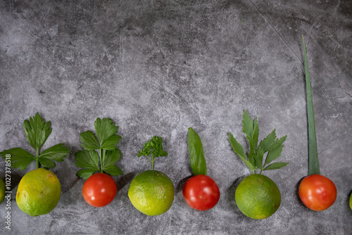 grüne und gelbe Limetten sowie Tomaten, Hintergrund grau