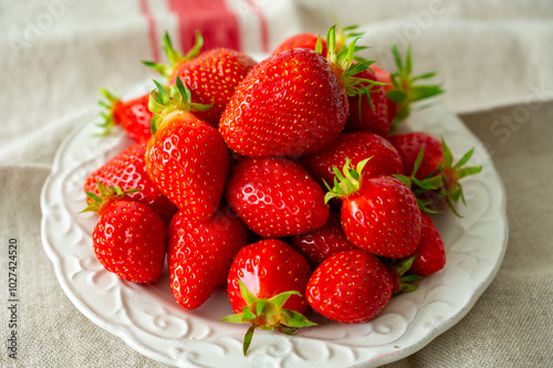 Plate with french organic red ripe sweet strawberries Fraises de Plougastel, harvested in France