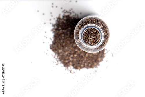 chia seeds in a transparent plastic bottle, isolated on a white background, spread outside the bottle photo