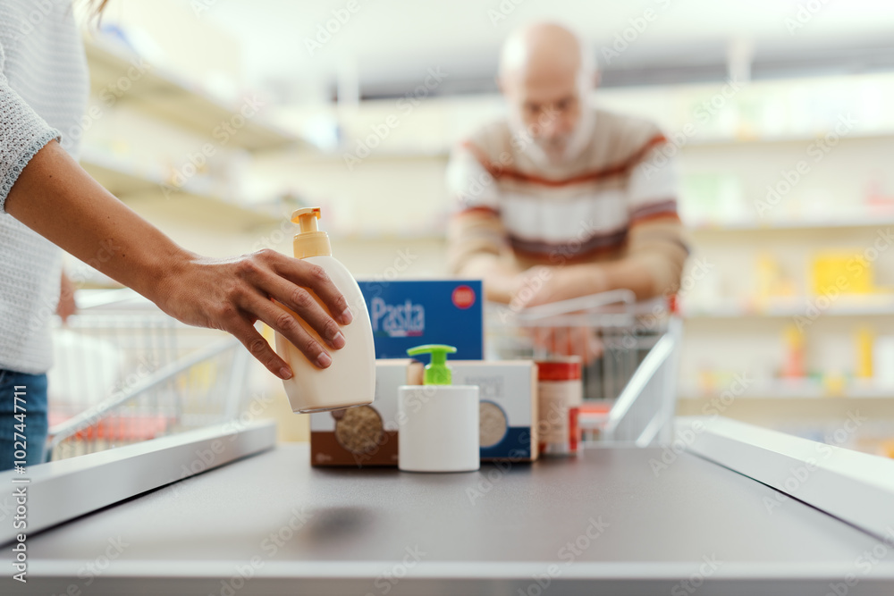 Customer placing groceries on the checkout conveyor belt Customer placing groceries on the checkout conveyor belt