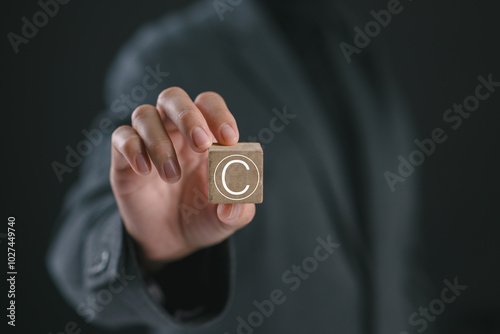 Person holding wooden block with copyright icon for author rights and patented intellectual property. copyleft trademark license. Copyright or patent concept. photo