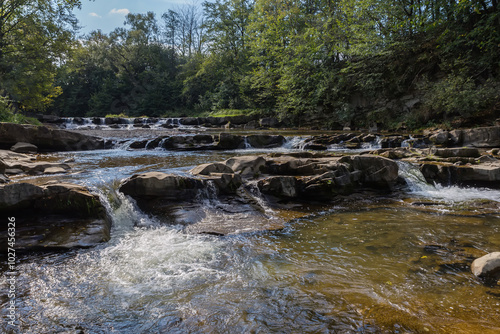 Small cascade waterfall on a mountain river in sunny day