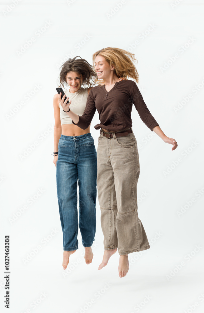 Happy young women using a smartphone and jumping Happy young women using a smartphone and jumping
