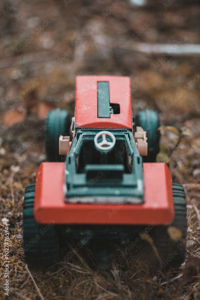 Closeup of a red toy tractor placed on the ground
