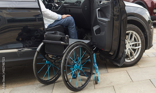 A male driver using a wheelchair is about to get out of his car