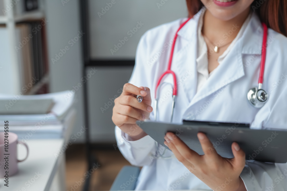Female doctor is smiling while taking notes on her clipboard during a workday at the hospital Female doctor is smiling while taking notes on her clipboard during a workday at the hospital