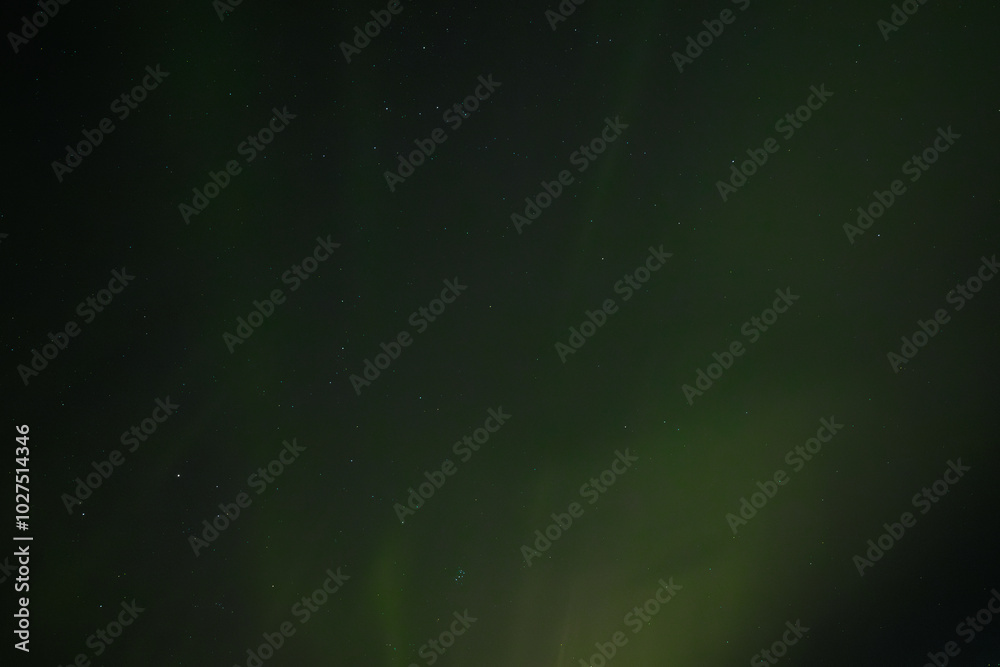 A peaceful display of the Aurora Borealis casts soft green light across the starry night sky. The gentle glow blends into the dark background, creating a serene and ethereal atmosphere.