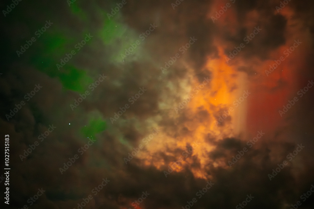 A captivating scene of the Aurora Borealis with vibrant red and orange hues illuminating the night sky. Dark clouds add drama, while subtle green light emerges through the atmosphere