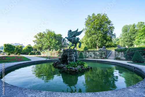 Mirabell Gardens, Salzburg, Austria - June 14, 2019: A pegasus(winged horse) statue perched on a small pond stone. photo