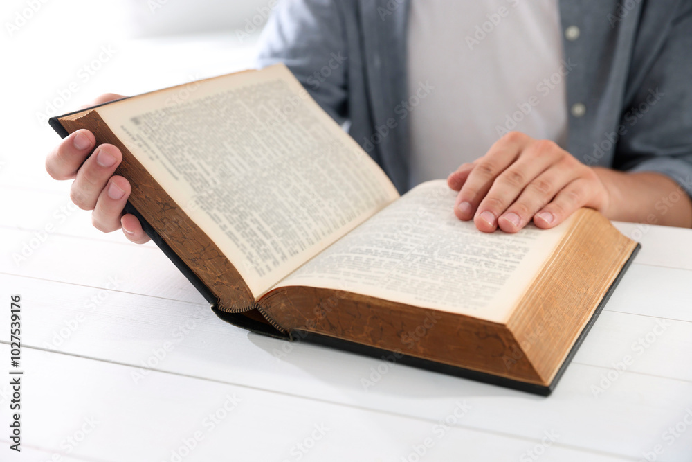 Fototapeta premium Man with Bible at white wooden table, closeup