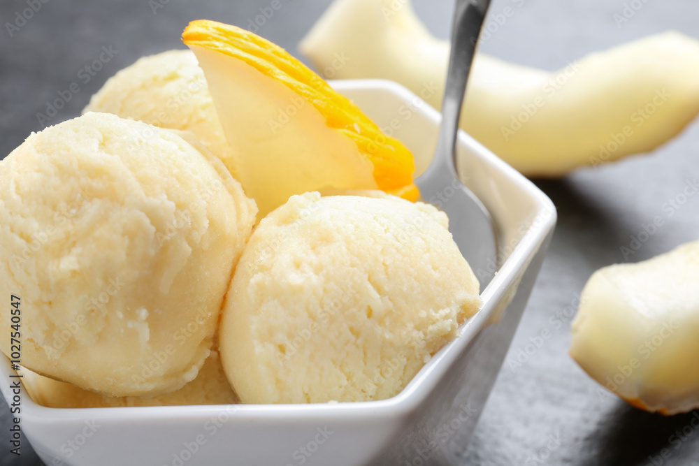 Scoops of tasty melon sorbet with fresh fruit and spoon in bowl on grey table, closeup Scoops of tasty melon sorbet with fresh fruit and spoon in bowl on grey table, closeup