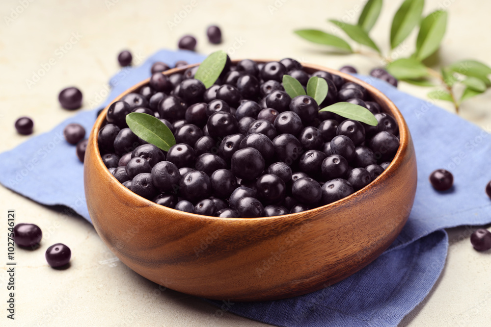 Ripe acai berries and leaves in bowl on grey table, closeup Ripe acai berries and leaves in bowl on grey table, closeup