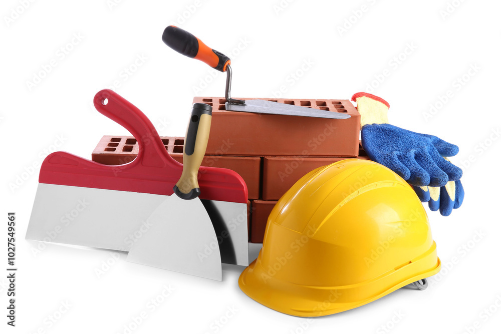 Fototapeta premium Yellow hard hat, red bricks, gloves, trowel and putty knives isolated on white. Building material and construction tools