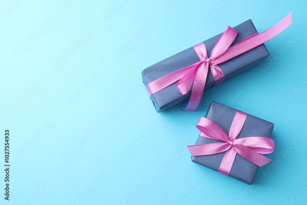 Gift boxes with bows on light blue background, flat lay. Space for text Gift boxes with bows on light blue background, flat lay. Space for text