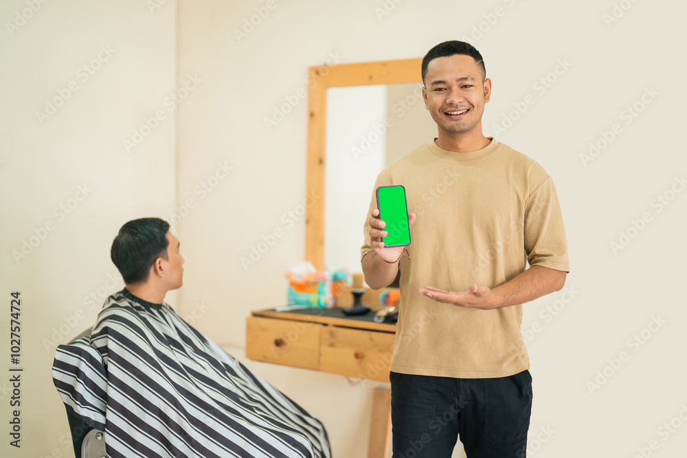 A man is sitting in a barbers chair, getting his hair cut, all the while holding a cell phone up to his ear for a call A man is sitting in a barbers chair, getting his hair cut, all the while holding a cell phone up to his ear for a call