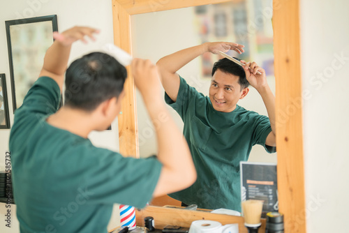 A man is carefully brushing his hair while standing in front of a mirror, taking his time to make sure he looks presentable and tidy photo