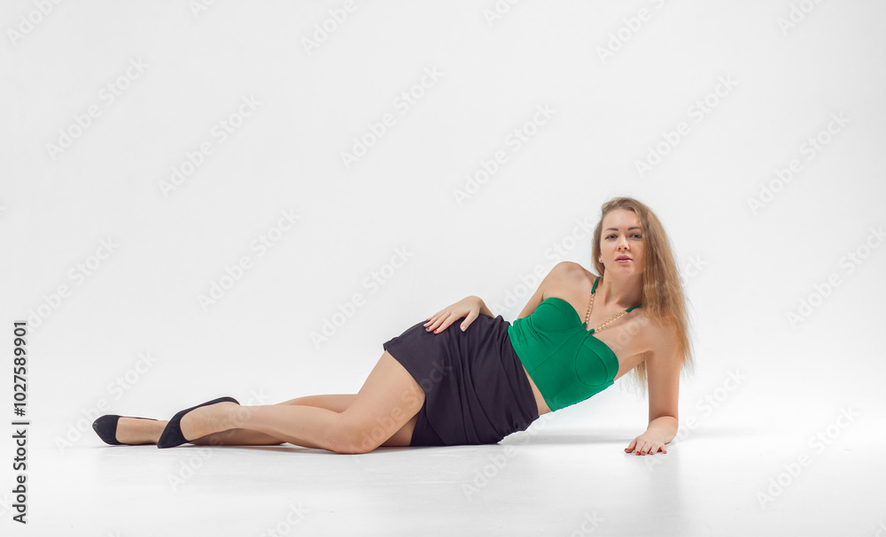 Woman in green top and black skirt posing in front of camera. She has long hair, she is standing on white background. Beautiful sexy body. Fitness and healthy eating concept. Woman in green top and black skirt posing in front of camera. She has long hair, she is standing on white background. Beautiful sexy body. Fitness and healthy eating concept.