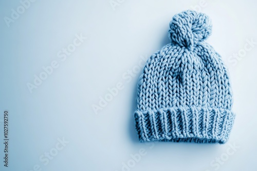 Cozy light blue knitted beanie hat resting on a soft surface.