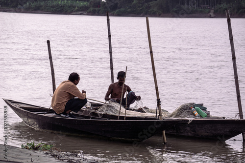 Gorai-Madhumati River. Fishing boat in the river. Fisherman is fixing the fishing net on the boat. The scene was captured on 24 October 2023 from Rajbari, Bangladesh. photo