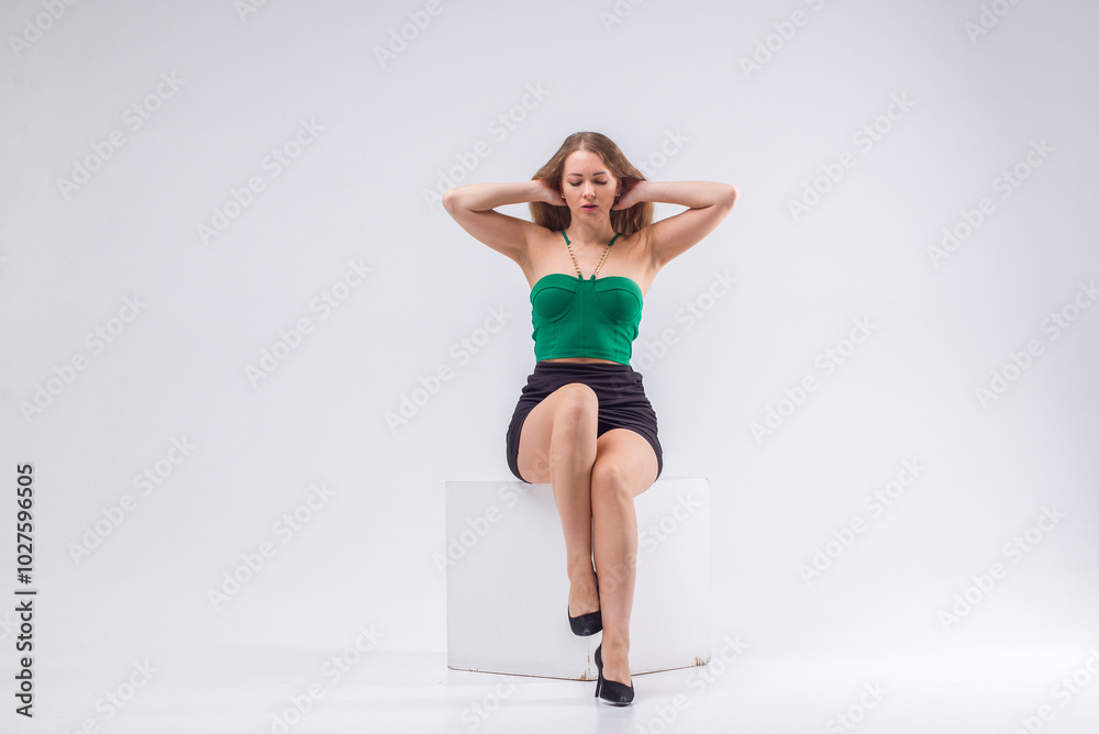 Woman in green top and black skirt posing in front of camera. She has long hair, she is standing on white background. Beautiful sexy body. Fitness and healthy eating concept. Woman in green top and black skirt posing in front of camera. She has long hair, she is standing on white background. Beautiful sexy body. Fitness and healthy eating concept.