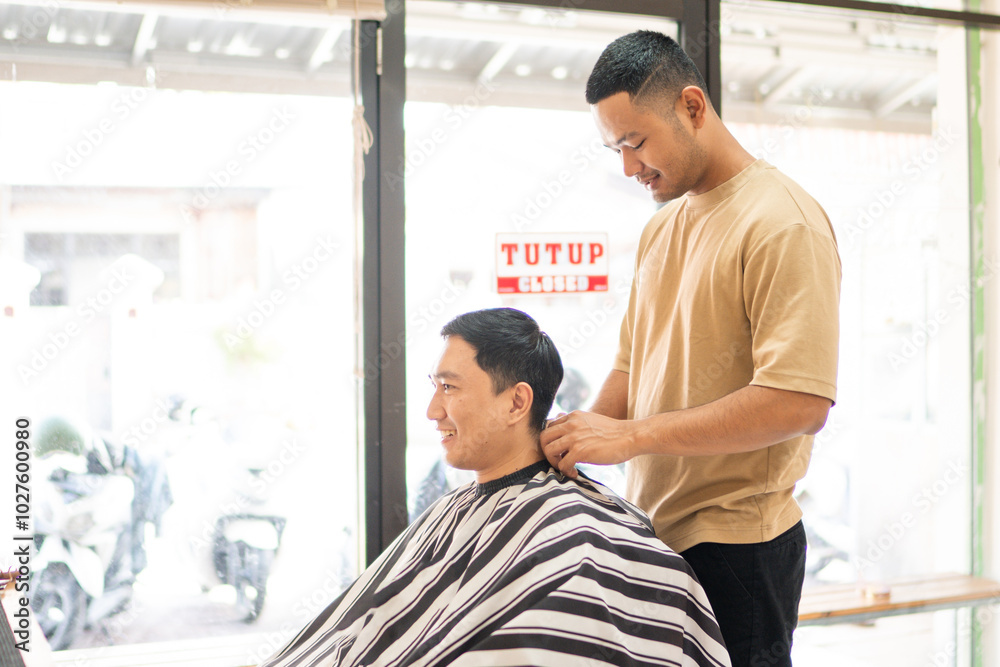 Obraz premium A man is currently enjoying the experience of getting his hair cut by a skilled barber inside a bustling barber shop that is welllit