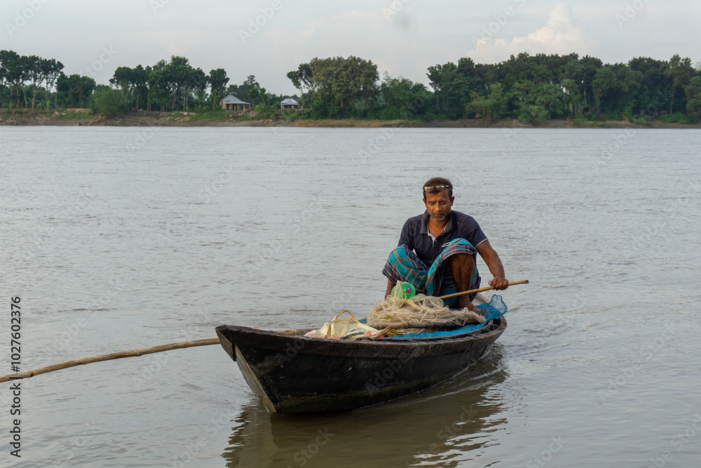 Gorai-Madhumati river of Bangladesh. Evening by the river. Fishermen are fishing in boats in the middle of the river. The river flows under the twilight sky. Gorai-Madhumati river of Bangladesh. Evening by the river. Fishermen are fishing in boats in the middle of the river. The river flows under the twilight sky.