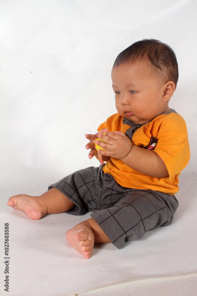 Adorable baby boy sitting and playing on white background Adorable baby boy sitting and playing on white background