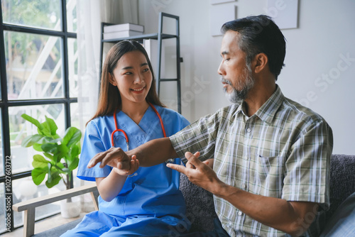 Young female nurse is checking the pulse of a senior patient, providing medical care and support at his home