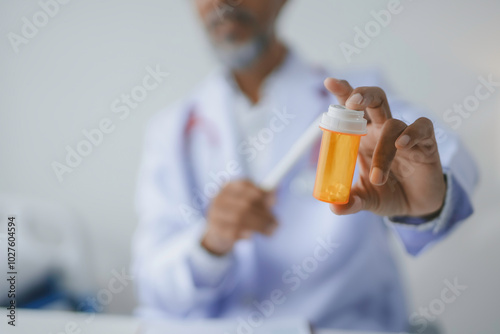 Medical doctor holding a pill bottle and recommending prescription medicine during a consultation