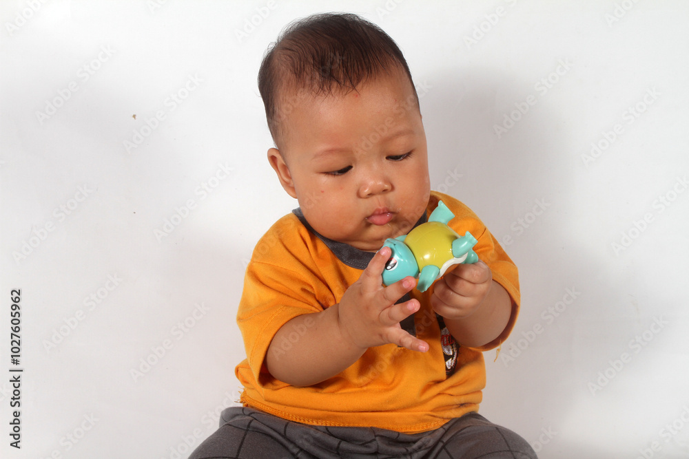 Adorable baby boy sitting and playing on white background Adorable baby boy sitting and playing on white background
