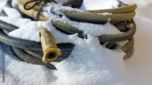 Winter, on the snow lies a thick hose, coiled into rings from a sandblasting machine, a Baynet type connection. photo