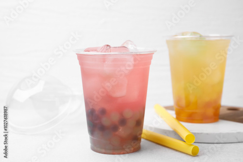 Tasty bubble tea in plastic cups and straws on light table, closeup