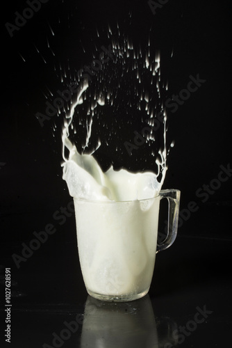 jarra de leche con salpicaduras, en fondo negro