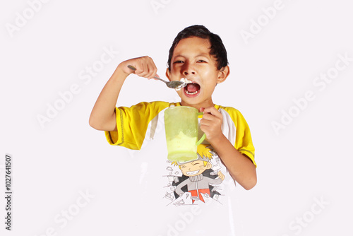 Handsome Indonesian boy, enjoying eating ice cream in a glass