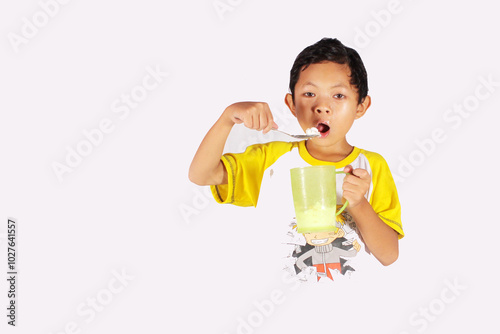 Handsome Indonesian boy, enjoying eating ice cream in a glass