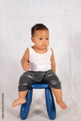 Adorable baby boy practicing standing on white background wearing white bra and shorts for healthy baby advertisement
