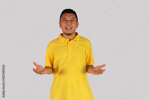 Asian mature man in yellow shirt smiling happily after getting a new idea with open arms pose and showing his idea