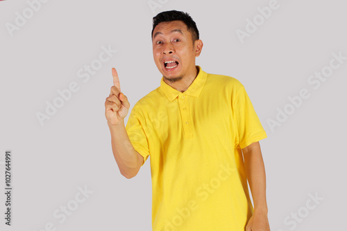 Asian mature man wearing yellow shirt smiling happily after getting a new idea
