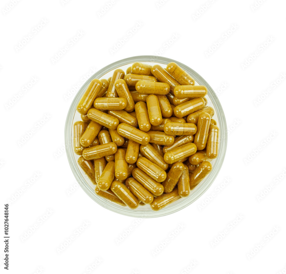 Top view of a group of turmeric herbal capsules in a small glass bowl on a white background. Top view of a group of turmeric herbal capsules in a small glass bowl on a white background.