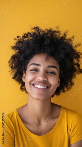 A joyful African-American woman smiles brightly against a solid yellow backdrop