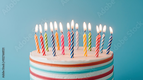 Colorful candles on a white cake, blue background, celebration, birthday joy. 
