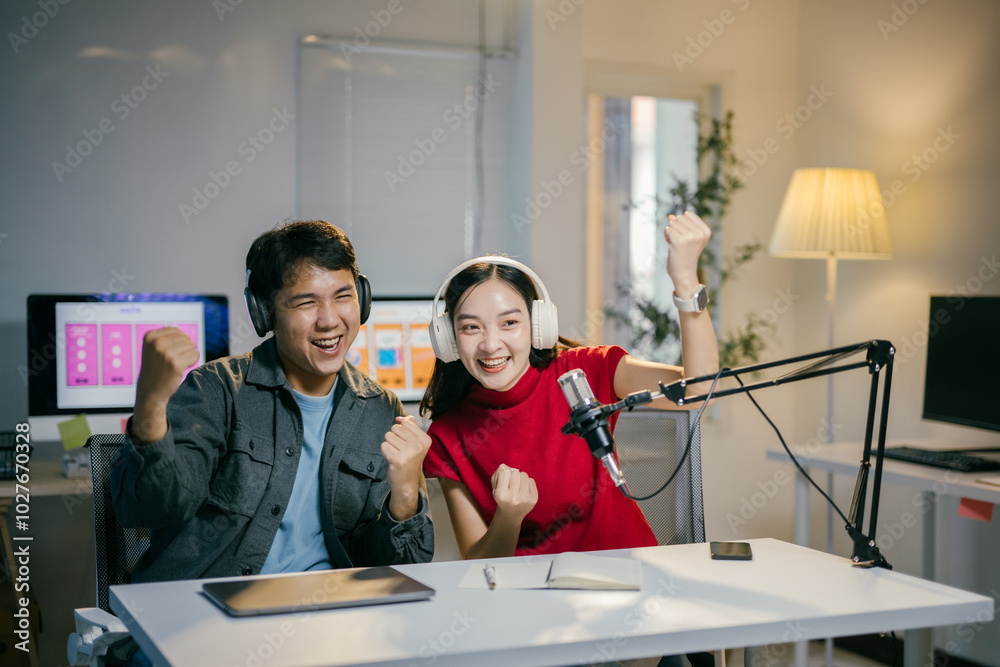 Obraz premium Two podcasters celebrating success in their recording studio, surrounded by technology, teamwork, and a cheerful modern lifestyle