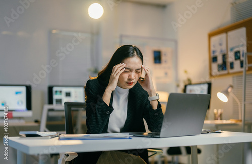 Stressed businesswoman at desk in modern office, exhausted and overwhelmed by work pressure, highlighting unhealthy work environment