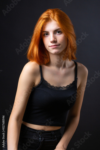 Cute red-haired girl, studio portrait on a black background.