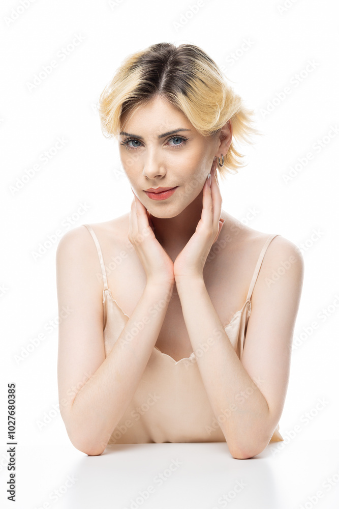 A young blonde girl with clear skin in a satin top. Beauty portrait of a woman on a white background in the studio. A young blonde girl with clear skin in a satin top. Beauty portrait of a woman on a white background in the studio.