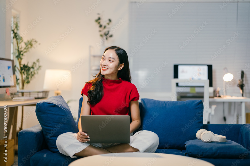 Young asian woman happily works on her laptop in her cozy home office, surrounded by modern design and natural light. She is fully immersed in her work, dressed casually and smiling Young asian woman happily works on her laptop in her cozy home office, surrounded by modern design and natural light. She is fully immersed in her work, dressed casually and smiling